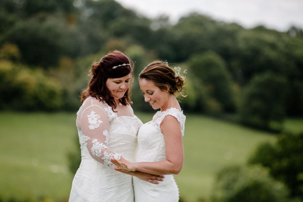 Two brides looking at their wedding ring on hand, in a field