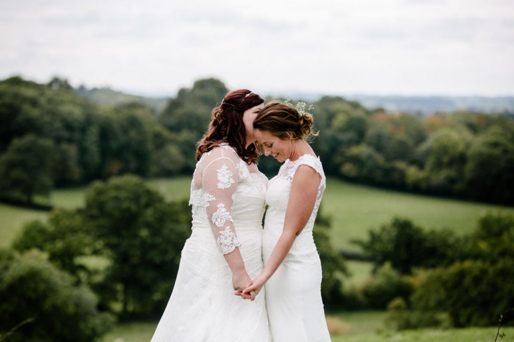 Two brides sharing a tender moment in a field