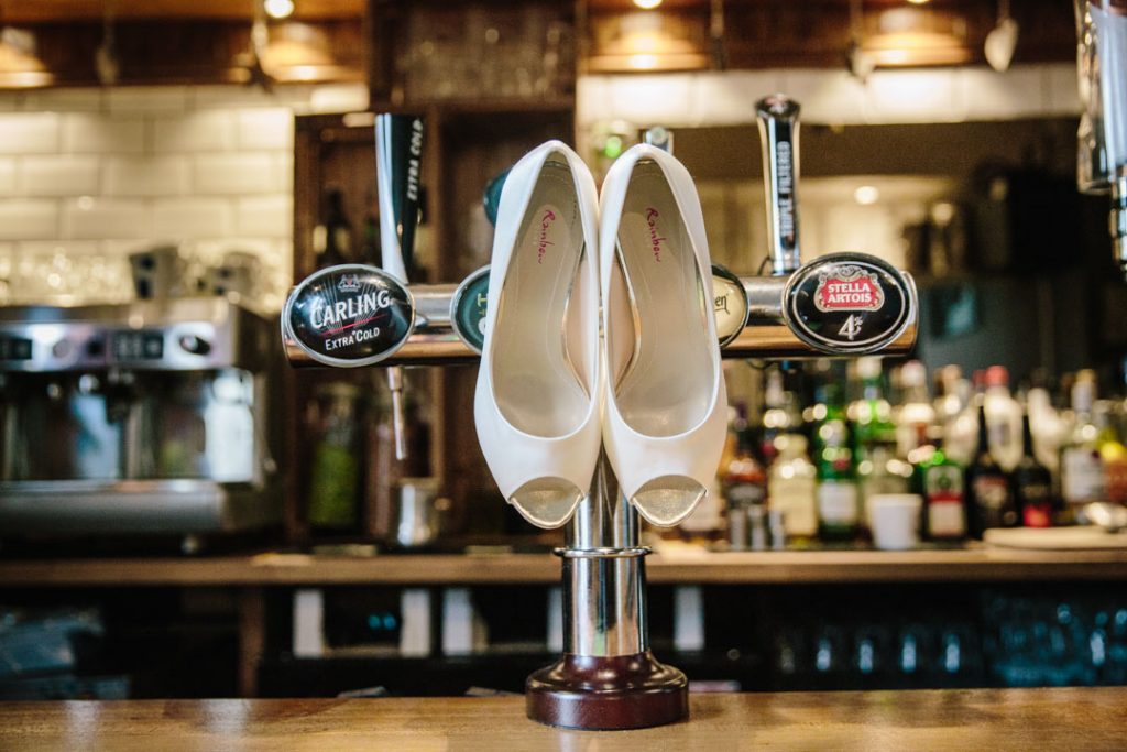 Wedding shoes hanging on a beer pump in a bar