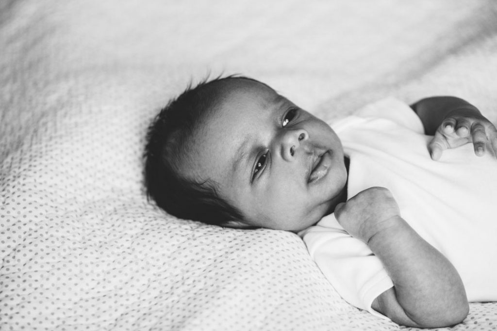black & white image of baby lying on the bed