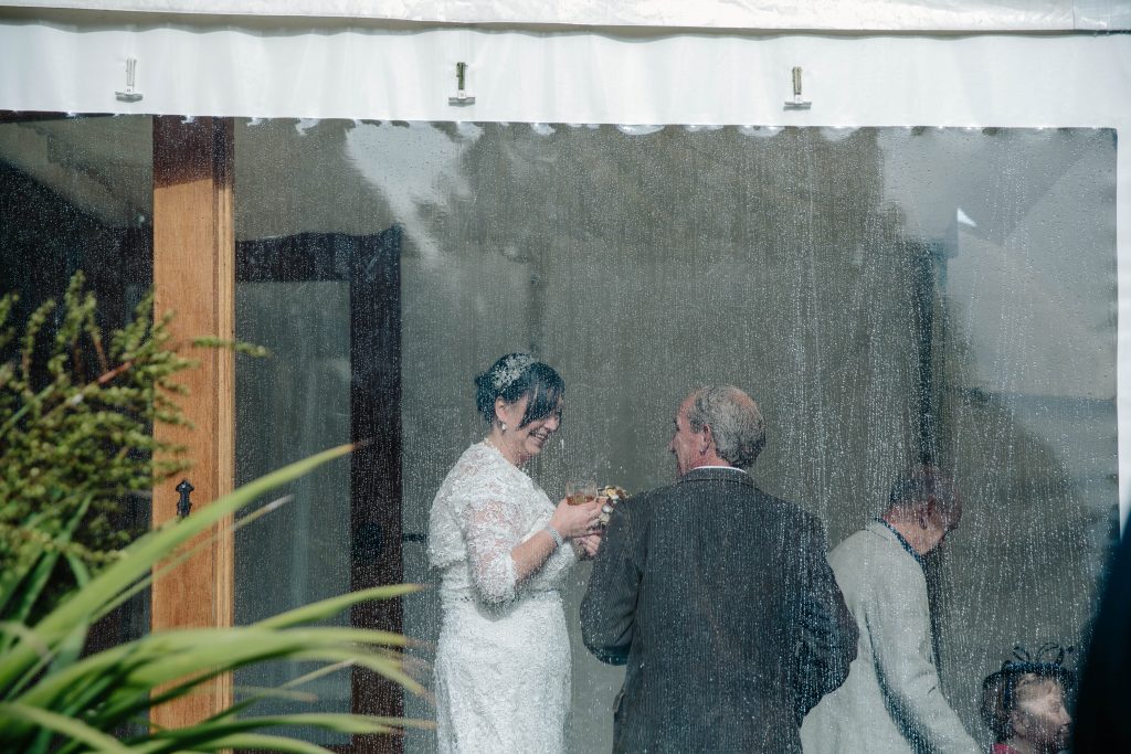 Bride chatting to guests, photographed through the window