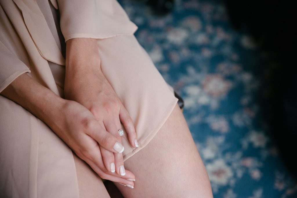 Brides hands in her lap, engagement ring showing on the morning of her wedding