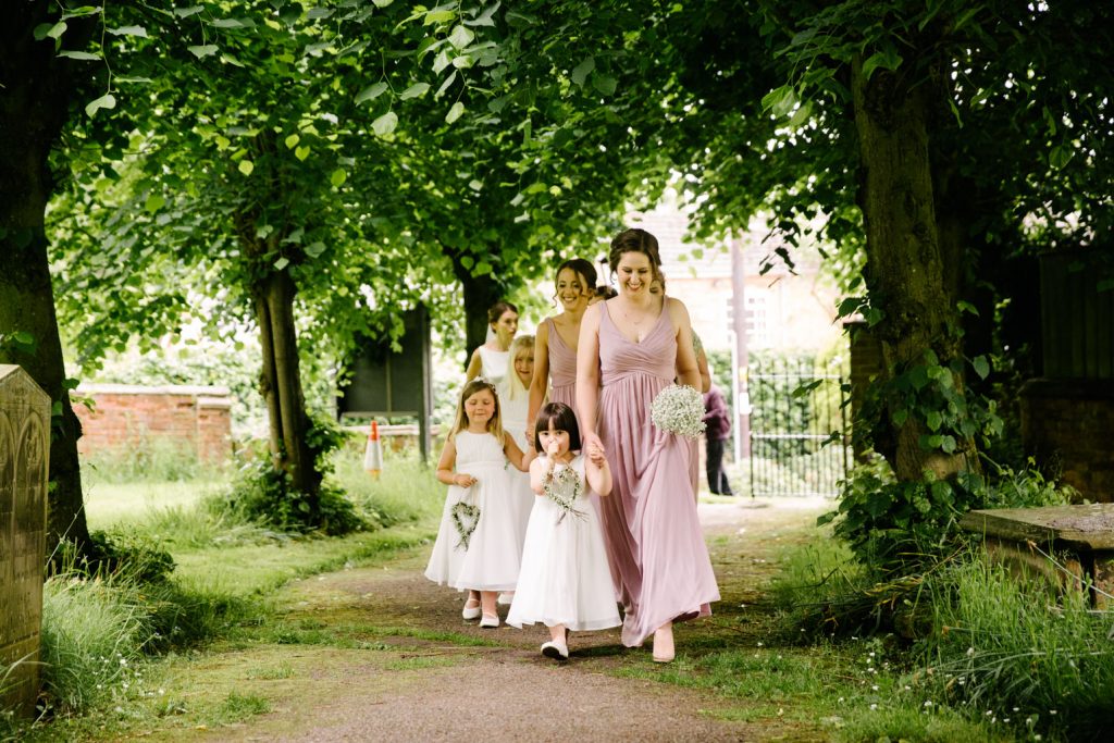 Bridesmaids walking up the path at church, ready for the ceremony