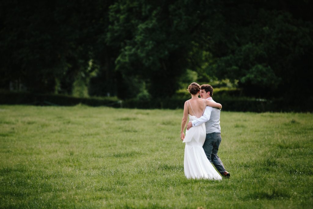 Bride and groom walking arm in arm across a field