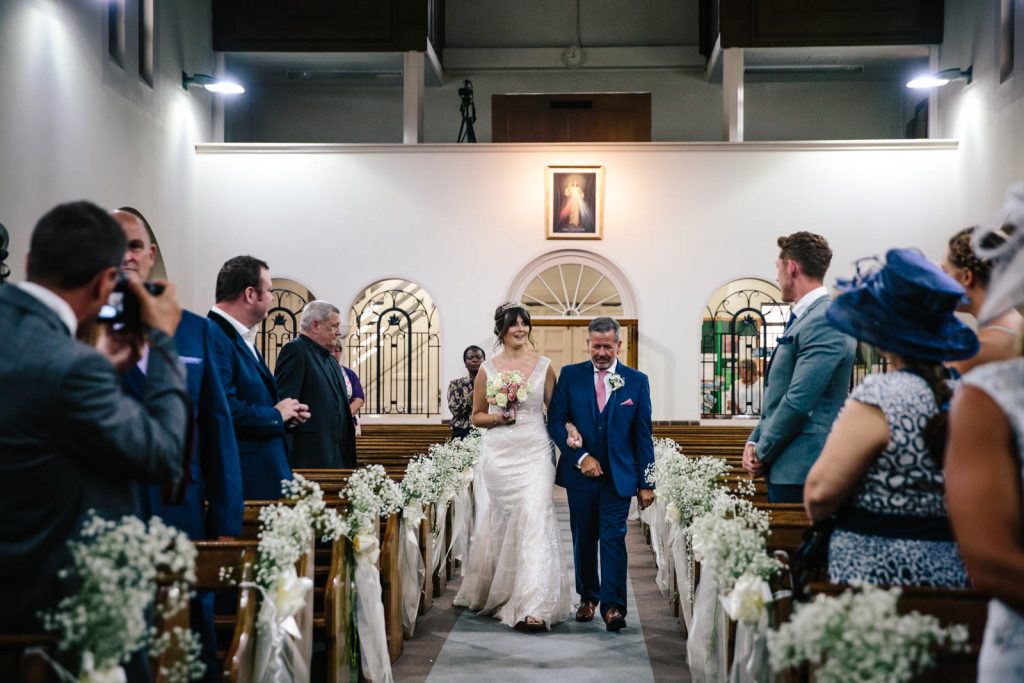 bride walking down the aisle with her father at church wedding