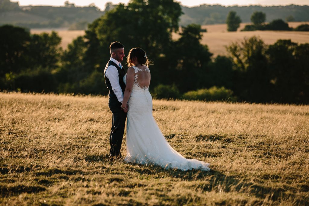 Bride & Groom standing together in a field at Dodford Manor wedding