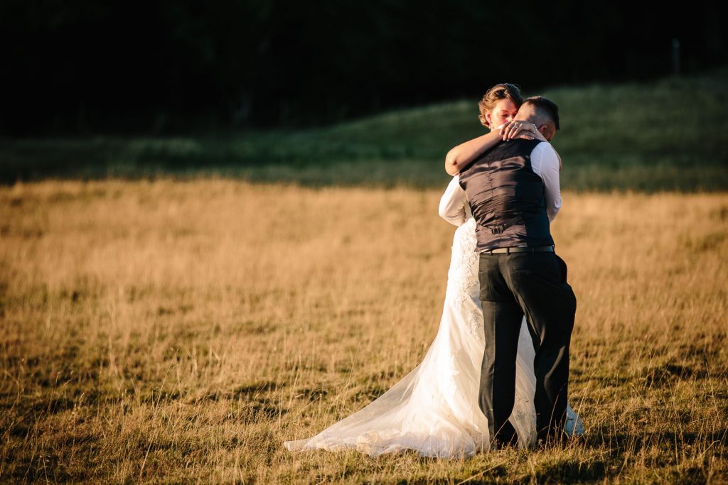 Bride & Groom cuddling in a field at dodford manor wedding
