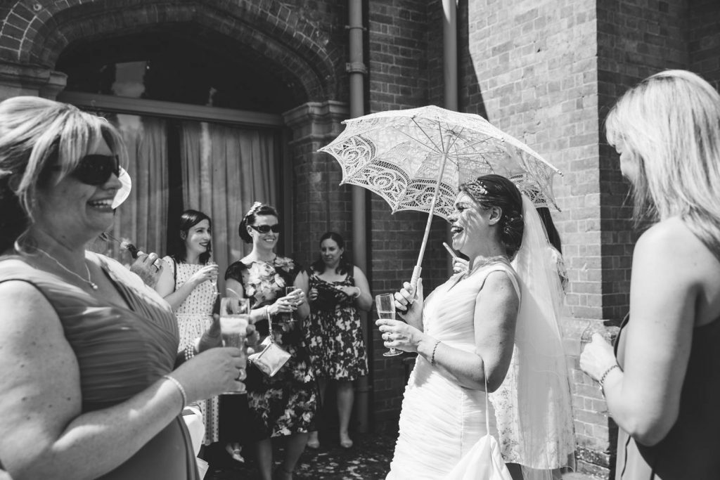 Bride laughing with sun parasol at The Wellcombe Hotel in Stratford in Arden 