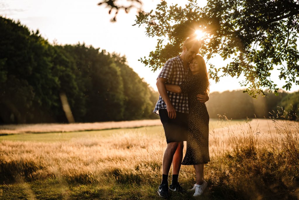 A backlight photograph of a couple cuddling in golden hour.