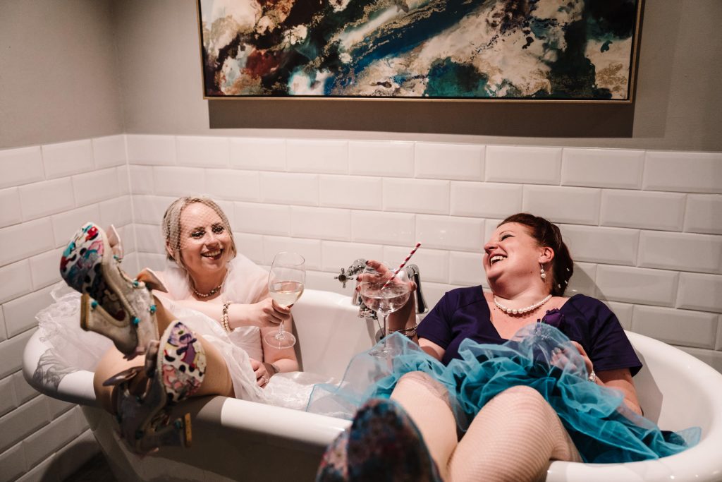 bride and bridesmaid sitting in a bath laughing at the townshouse