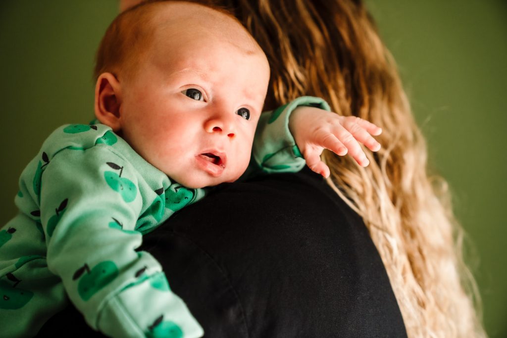 baby boy looking over Mum's shoulder during photoshoot  
