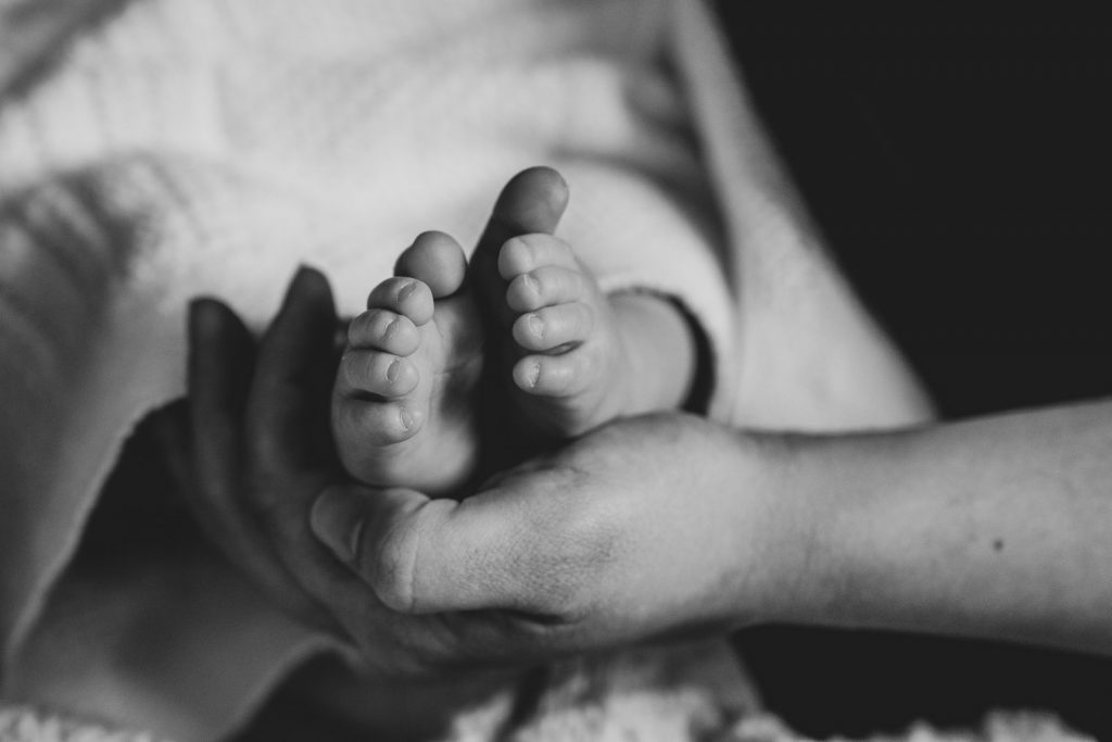 black and white image of mums hand holding her baby's feet 