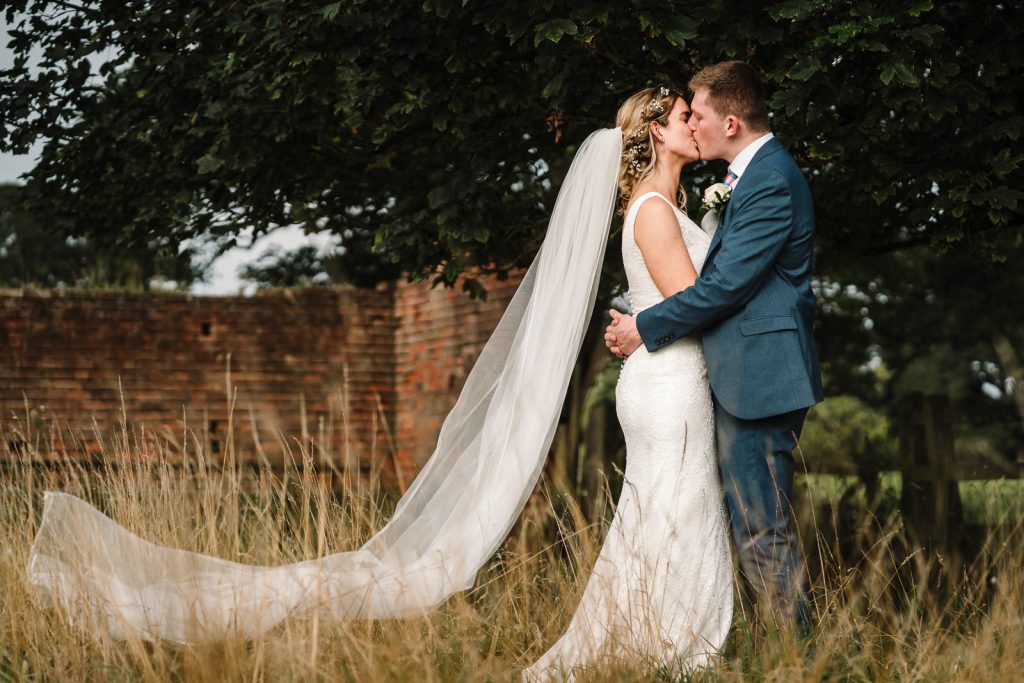 bride and groom kissing in field at cattows farm wedding venue