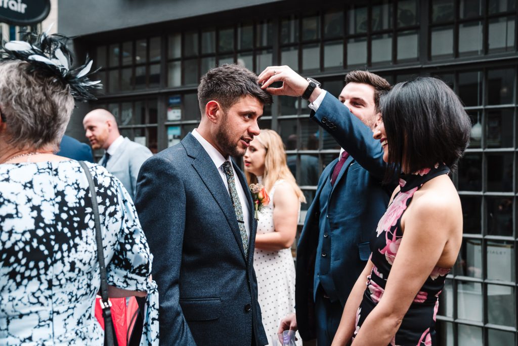 guest picking confetti out of grooms hair, Digbeth wedding 