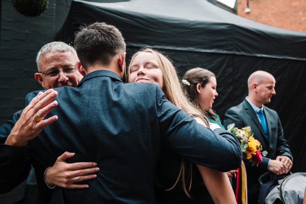 groom hugging guests at wedding drinks reception