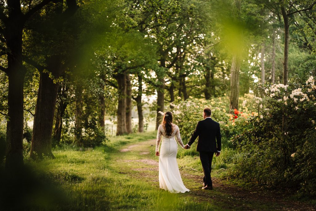 bride and groom walking through the trees at sunset