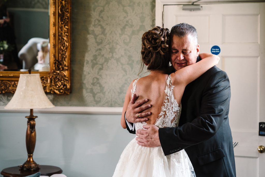 dad hugging daughter as he sees her in her wedding dress on wedding morning