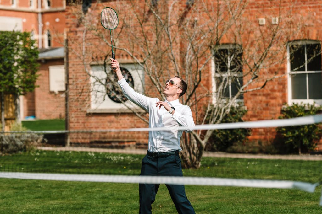 guest playing badminton in garden at stanbrook abbey wedding