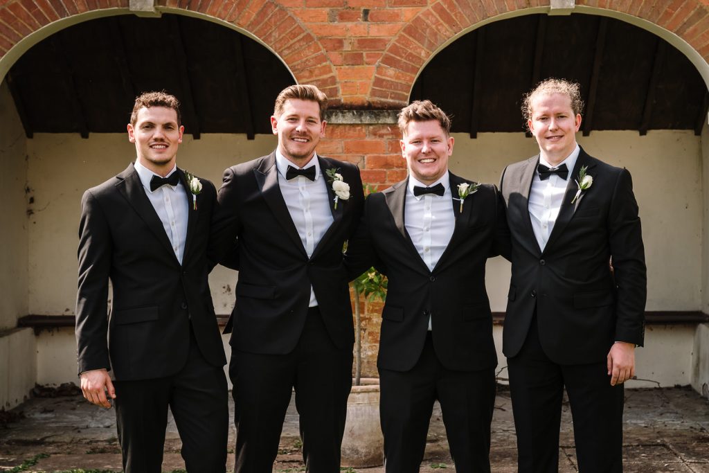 groomsmen smiling for a photo at stanbrook abbey wedding