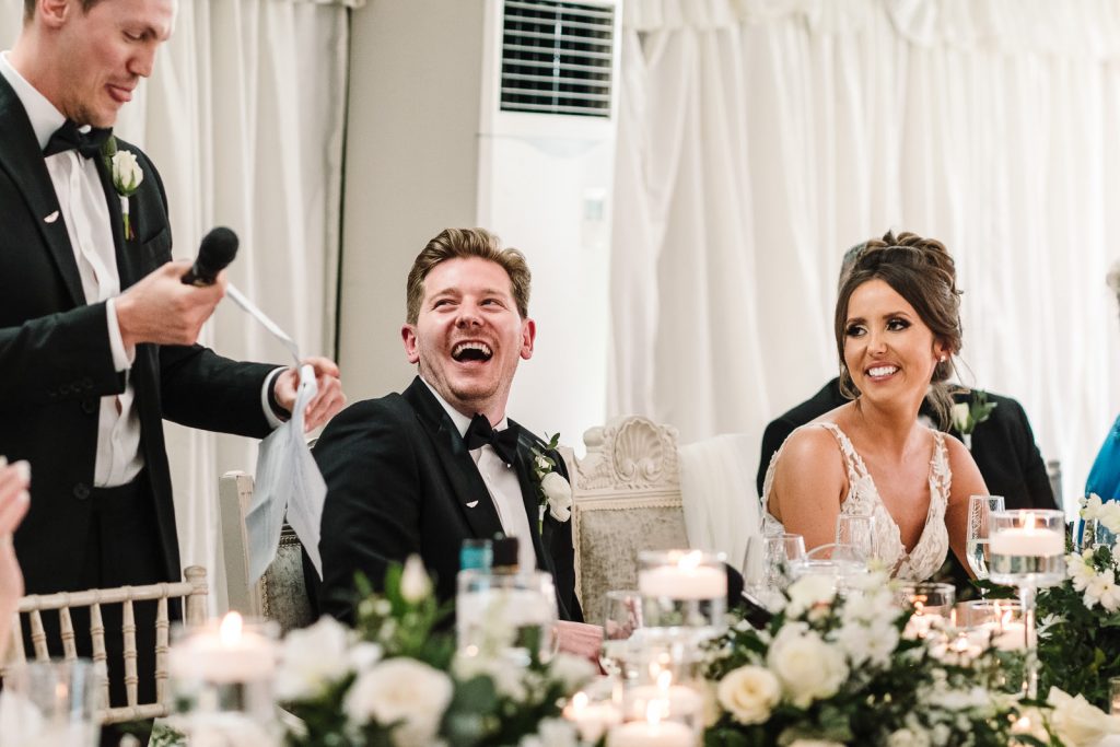 bride and groom laughing at best mans speech